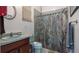 Dated bathroom featuring a tub with shower, basin, and sunflower curtain at 23321 N Buckhill Rd, Howey In The Hills, FL 34737