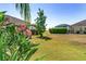 Lush backyard featuring vibrant pink flowers, with a partial view of a screened-in pool area at 1786 Red Clover Ln, The Villages, FL 32163