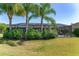 Lush backyard featuring a screened-in pool area surrounded by mature landscaping and palm trees at 1786 Red Clover Ln, The Villages, FL 32163