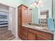 Bathroom with granite counter tops, wood cabinets, large mirror, modern fixtures and a view of the bedroom at 1786 Red Clover Ln, The Villages, FL 32163