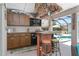Inviting outdoor kitchen offers a mini fridge, cabinetry, and bar seating overlooking the pool at 1786 Red Clover Ln, The Villages, FL 32163