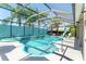 Sparkling screened-in pool featuring a colorful turquoise fence and inviting lounge chairs at 1786 Red Clover Ln, The Villages, FL 32163