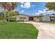 Tan single story home with carport and well-manicured lawn at 1653 Kiley Ct, The Villages, FL 32159