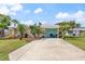 Tan single story home with teal garage door, landscaping, and long driveway at 48 Palm Dr, Ormond Beach, FL 32176