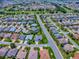 A high-definition aerial view shows a neighborhood with beautiful landscaping near a golf course at 1751 Ashwood Run, The Villages, FL 32162