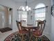 Cozy dining room with wooden table and chairs, a decorative chandelier, and two arched windows letting in ample light at 1751 Ashwood Run, The Villages, FL 32162