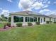 Back exterior featuring a lush lawn, well-manicured landscaping, and solar panels at 1751 Ashwood Run, The Villages, FL 32162