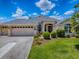 Charming single-story home featuring a three-car garage, landscaped yard, and arched entryway at 1751 Ashwood Run, The Villages, FL 32162