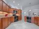 Well-equipped kitchen with warm wood cabinetry, black appliances, tile backsplash, and granite countertops at 1751 Ashwood Run, The Villages, FL 32162