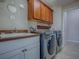 Bright laundry room features a modern washer and dryer, storage cabinets, and convenient sink at 1751 Ashwood Run, The Villages, FL 32162