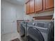 Functional laundry room with modern washer and dryer, overhead cabinets, and utility sink at 1751 Ashwood Run, The Villages, FL 32162