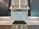 Gas cooktop with stainless steel range hood and marble backsplash at 16122 Pendio Dr, Bella Collina, FL 34756