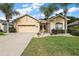 Tan house with two-car garage and nicely landscaped yard at 16984 Se 109Th Ave, Summerfield, FL 34491