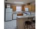 Cozy kitchen with wood cabinets, white appliances, and an eat-in bar at 9215 Se 177Th Simons Ln, The Villages, FL 32162