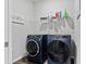 Laundry room with gray walls, blue front loading washer and dryer, and a shelf for storage at 6834 Mossy Oak Ln, Lakeland, FL 33810