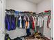 Walk-in closet with a closet rack filled with hanging shirts and jackets and a shelf with shoes at 6834 Mossy Oak Ln, Lakeland, FL 33810