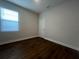 Bedroom with dark wood floors, neutral walls, window, and white door at 2252 Juniper Berry Dr, Minneola, FL 34715