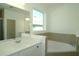 Bathroom featuring a soaking tub, large mirror and sink with white cabinets and stylish fixtures at 2311 Juniper Berry Dr, Minneola, FL 34715