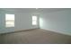 A carpeted bedroom with two large windows, providing ample natural light and open space at 2311 Juniper Berry Dr, Minneola, FL 34715