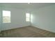 A bright carpeted bedroom with large windows, offering a clear view of the natural surroundings at 2311 Juniper Berry Dr, Minneola, FL 34715