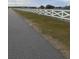 White fence lines a paved road leading to a large grassy lot at 10739 Fiesta St, Clermont, FL 34711