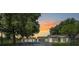 Charming single-story home with a detached garage and metal gate entrance, set against a sunset backdrop at 13832 Bay Lake Rd, Groveland, FL 34736