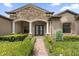 Elegant home exterior with stone accents, arched entryway, and landscaped walkway at 25499 Hawks Run Ln, Sorrento, FL 32776