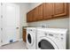 Laundry room with washer, dryer, and wooden cabinets at 25499 Hawks Run Ln, Sorrento, FL 32776