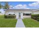 Close up of inviting home entrance with well-manicured shrubs and stylish black and white striped awnings over the windows at 17574 Se 106Th Ave, Summerfield, FL 34491