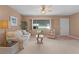 Cozy living room with neutral carpet, cream sofa, ceiling fan, and a large window at 17574 Se 106Th Ave, Summerfield, FL 34491