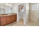 Bathroom with double sinks, granite countertop and wood cabinets, featuring a walk-in shower at 3732 Barrel Loop, The Villages, FL 32163