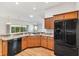 Kitchen with wood cabinets, granite counters, and black appliances at 3732 Barrel Loop, The Villages, FL 32163