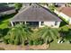 An aerial view showcases a home with a screened lanai, mature palms, and a well manicured yard at 1338 Neuport Path, The Villages, FL 32163