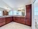 Bathroom features dual sinks, spacious dark wood cabinets, and tile floors with decorative lighting fixtures at 1338 Neuport Path, The Villages, FL 32163