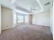 Spacious primary bedroom featuring a tray ceiling, a ceiling fan, and large windows that flood the space with natural light at 1338 Neuport Path, The Villages, FL 32163