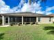 Rear exterior view of home showing enclosed lanai, manicured lawn, and neatly trimmed bushes at 1338 Neuport Path, The Villages, FL 32163