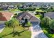 Stunning aerial view of home featuring beautiful lawn, mature palms, and a wide driveway leading to a spacious three-car garage at 1338 Neuport Path, The Villages, FL 32163