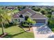 Beautifully landscaped home featuring mature palms, a pristine lawn, and a wide driveway leading to a spacious three-car garage at 1338 Neuport Path, The Villages, FL 32163