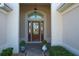 Inviting front entryway features a beautiful wood door with decorative glass inserts, flanked by columns and potted plants at 1338 Neuport Path, The Villages, FL 32163