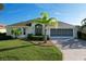 Charming single-story home with well-manicured lawn, mature landscaping, and spacious driveway leading to a two-car garage at 1338 Neuport Path, The Villages, FL 32163