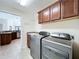 Laundry room featuring stainless steel washer and dryer, sink, cabinet space, and adjacent door to the house at 1338 Neuport Path, The Villages, FL 32163