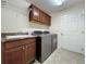 Well-equipped laundry room with sink, cabinets, and a modern washer and dryer set for convenience at 1338 Neuport Path, The Villages, FL 32163