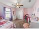 Bright bedroom featuring pink walls, plush carpet, and a ceiling fan at 8830 Se 161St Pl, Summerfield, FL 34491