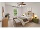 Cozy bedroom with a decorative headboard, ceiling fan, and large window offering views of the landscape at 8566 Se 156Th Pl, Summerfield, FL 34491
