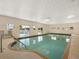 A relaxing indoor pool area with clear water, steps, and large windows for natural light in a community recreation center at 1209 Apache Cir, Tavares, FL 32778