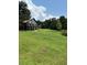Picturesque home with a lush green lawn and a backdrop of mature trees and blue sky at 26348 Se Highway 42, Umatilla, FL 32784