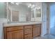 Bathroom with double sinks, a large mirror, a door and a partial view of the walk-in shower at 3114 Jemima Ave, The Villages, FL 32163