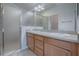 A well-lit bathroom featuring double sinks, a large mirror, and a glass shower enclosure at 3114 Jemima Ave, The Villages, FL 32163