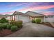 Charming single-story home at dusk with a two-car garage, landscaped front yard, and a paved driveway at 3114 Jemima Ave, The Villages, FL 32163