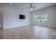 Bright living room features wood flooring, large window, a ceiling fan, and a mounted television at 3114 Jemima Ave, The Villages, FL 32163